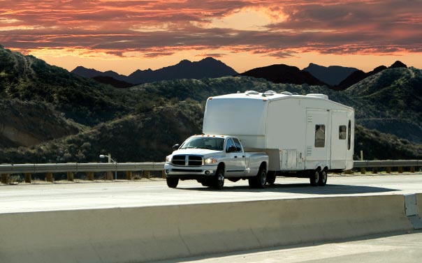 silver SUV pulling 5th wheel trailer in desert